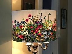 a lamp that is sitting on top of a table next to a wall with flowers painted on it