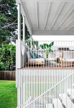 an outdoor living area with white furniture and green grass on the side of the house