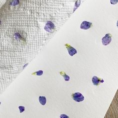 two sheets with purple flowers on them and one sheet has white paper under the covers