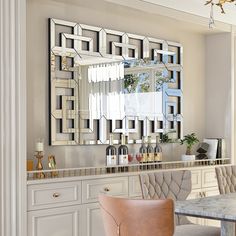 a dining room table with chairs and a large mirror on the wall above it's counter