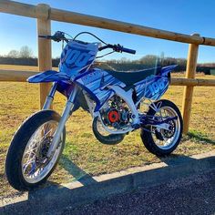 a blue dirt bike parked next to a wooden fence