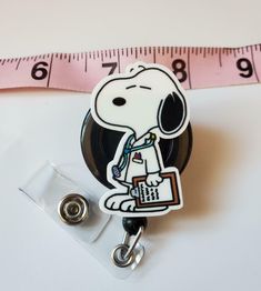 a badge with a cartoon character on it next to a measuring tape and a clip