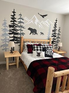 a bed room with a neatly made bed and a mountain mural on the wall behind it