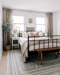 a bed room with a neatly made bed and a wooden bench in front of the window