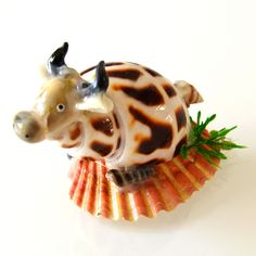 a toy cow sitting on top of a shell