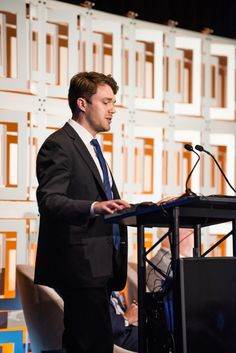 a man in a suit and tie standing at a podium