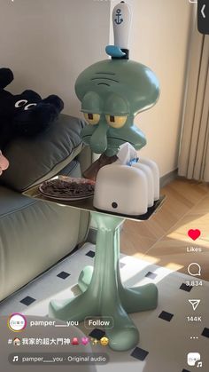 an octopus holding a tray with food on it in front of a couch and window