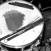 a black and white photo of a drum with sticks sticking out of the top side