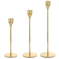 three brass colored candlesticks are standing in the middle of a white background and one is