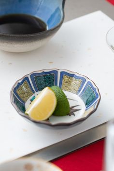 a small bowl with a lemon and a lime in it sitting on a white table