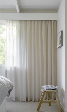 a bed room with a neatly made bed next to a window and a white curtain