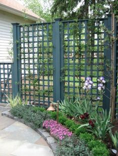 a garden area with flowers and plants in the center, next to a green fence