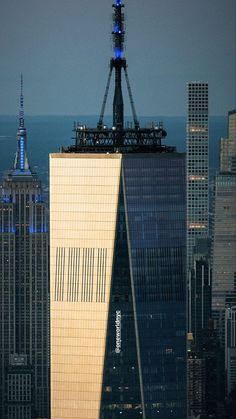 an airplane flying over the top of a tall building with skyscrapers in the background