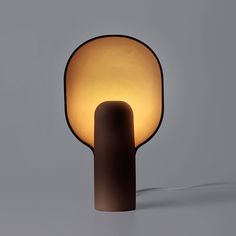 a lamp that is sitting on top of a table next to a gray wall and floor