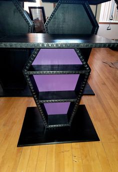 a purple shelf sitting on top of a hard wood floor next to a wooden table