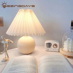 an open book sitting on top of a table next to a lamp and a small figurine