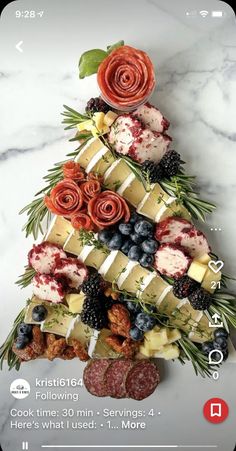 a christmas tree made out of fruits and cheeses on a marble counter top with greenery