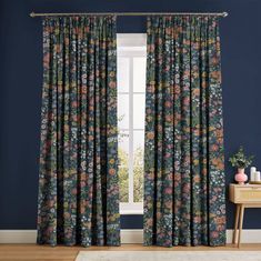 a living room with dark blue walls and floral curtains, along with a rug on the floor