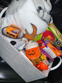 a stuffed animal sitting inside of a white box filled with candy and candies on top of a black leather chair