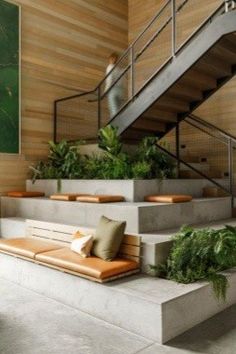 an indoor area with stairs, plants and couches on the concrete steps leading up to the second floor