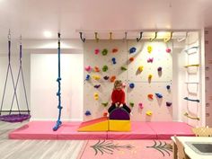 a woman sitting on top of a purple chair in front of a wall with climbing ropes