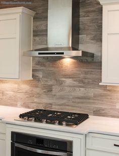 a stove top oven sitting inside of a kitchen next to white cabinets and counter tops