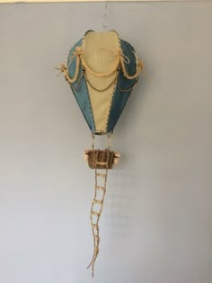 a blue and yellow hot air balloon hanging on the wall with ropes attached to it