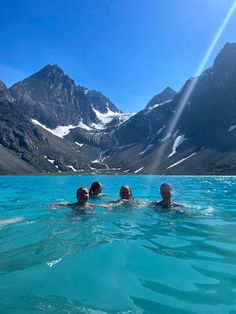 three people floating in the water near mountains