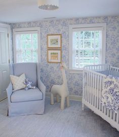 a baby's room decorated in blue and white with a giraffe statue