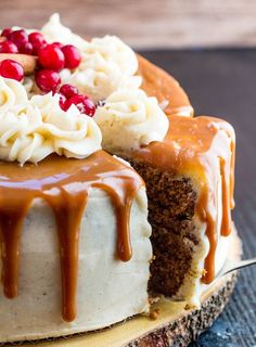 a cake covered in icing and toppings on top of a wooden board with a fork