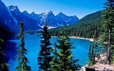 a lake surrounded by trees and mountains in the background