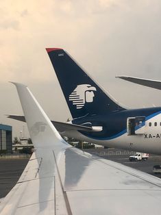 the tail end of an airplane as it sits on the tarmac next to another plane