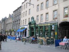 people are sitting at tables in front of buildings