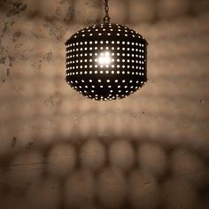 a black and white polka dot light hanging from a chain on a brick wall,