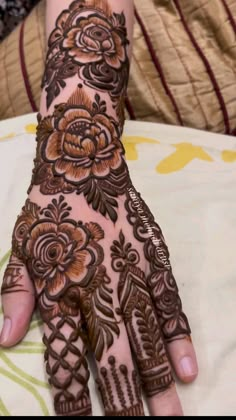 a woman's hand with henna tattoos on her fingers and hands, all decorated with flowers