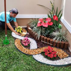 a man kneeling down next to a garden with flowers and plants in the middle of it