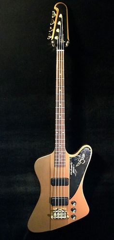 an electric bass guitar hanging on a black wall in a room with dark walls and flooring