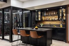 a wine cellar in the middle of a kitchen with bar stools and shelves full of bottles