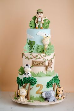 a three tiered cake decorated with animals and jungles on it's sides