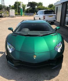 a green sports car is parked in front of a building with other cars behind it