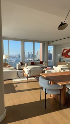 a living room filled with furniture and large windows overlooking the cityscape in the distance