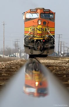 an orange and yellow train traveling down tracks