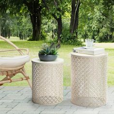 two white stools sitting next to each other on a brick patio with trees in the background