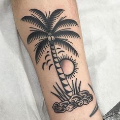 a black and white palm tree tattoo on the arm