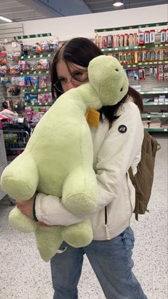 a woman holding a large green teddy bear