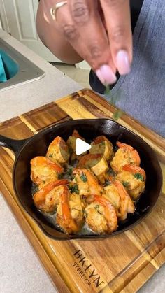 a person cooking food in a skillet on top of a cutting board with a knife