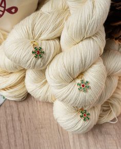 several skeins of white yarn with green and red decorations on them next to a bag