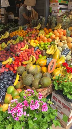 there are many different fruits and vegetables on display at the market stall, including bananas, melons, oranges, avocados, and other fruit