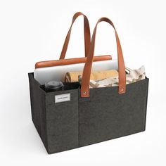 a black bag with two brown handles and some papers in it on a white background