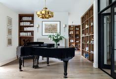 a grand piano in the middle of a room with bookshelves on either side